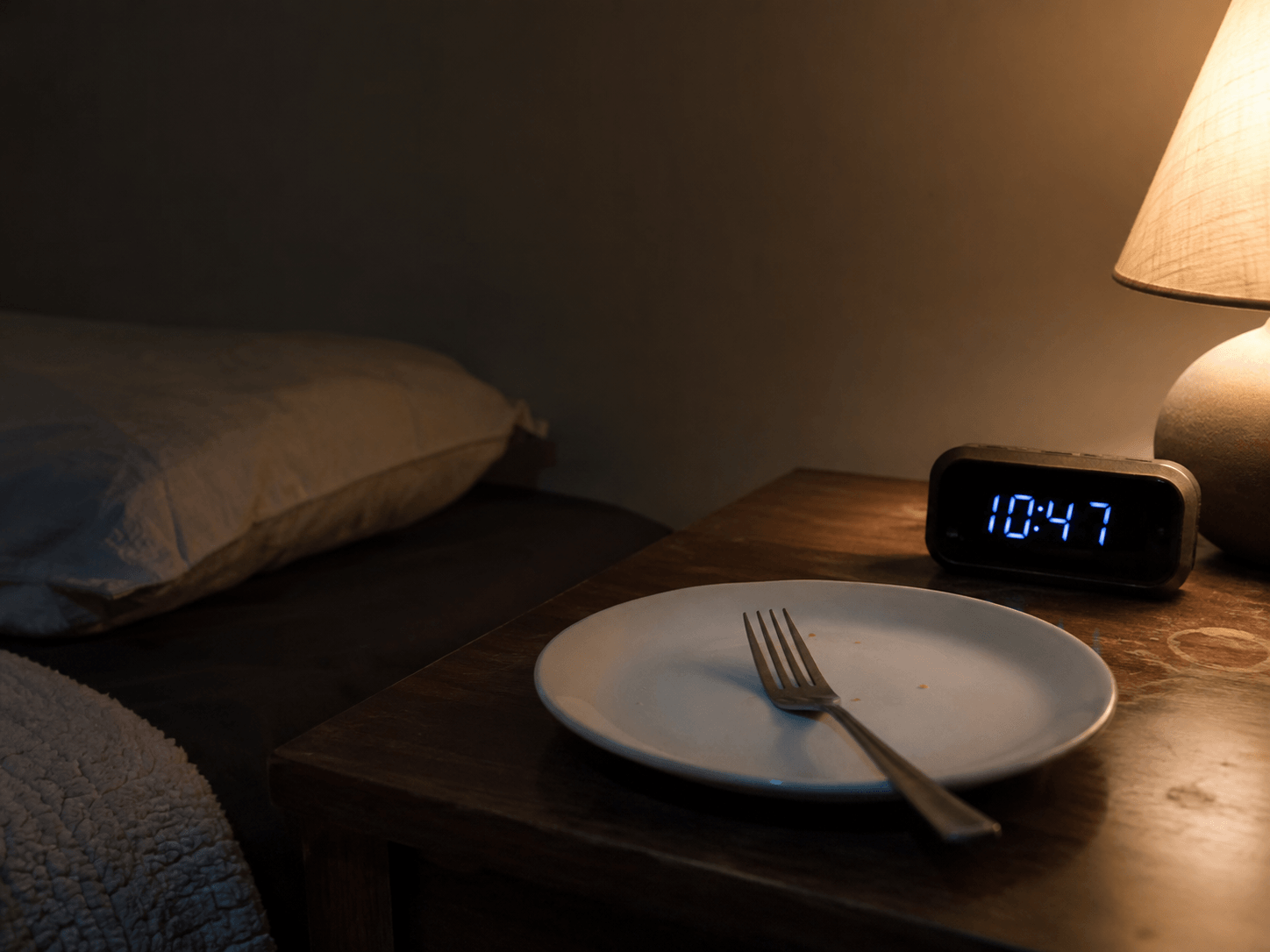 Clock on a nightstand next to a plate showing the gap between dinner and bedtime for acid reflux diet plan