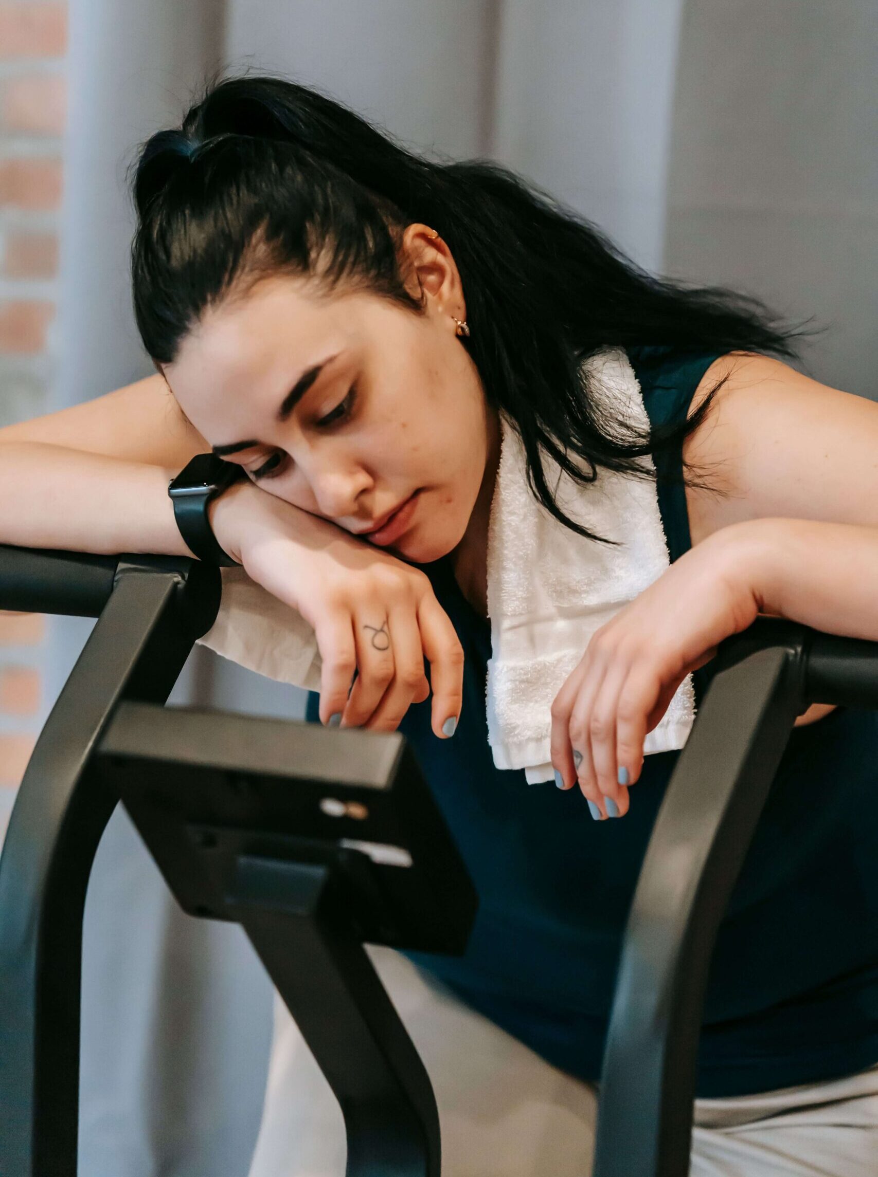 : Tired woman resting on an exercise bike after a workout, questioning if her bicycle workout for weight loss is actually working