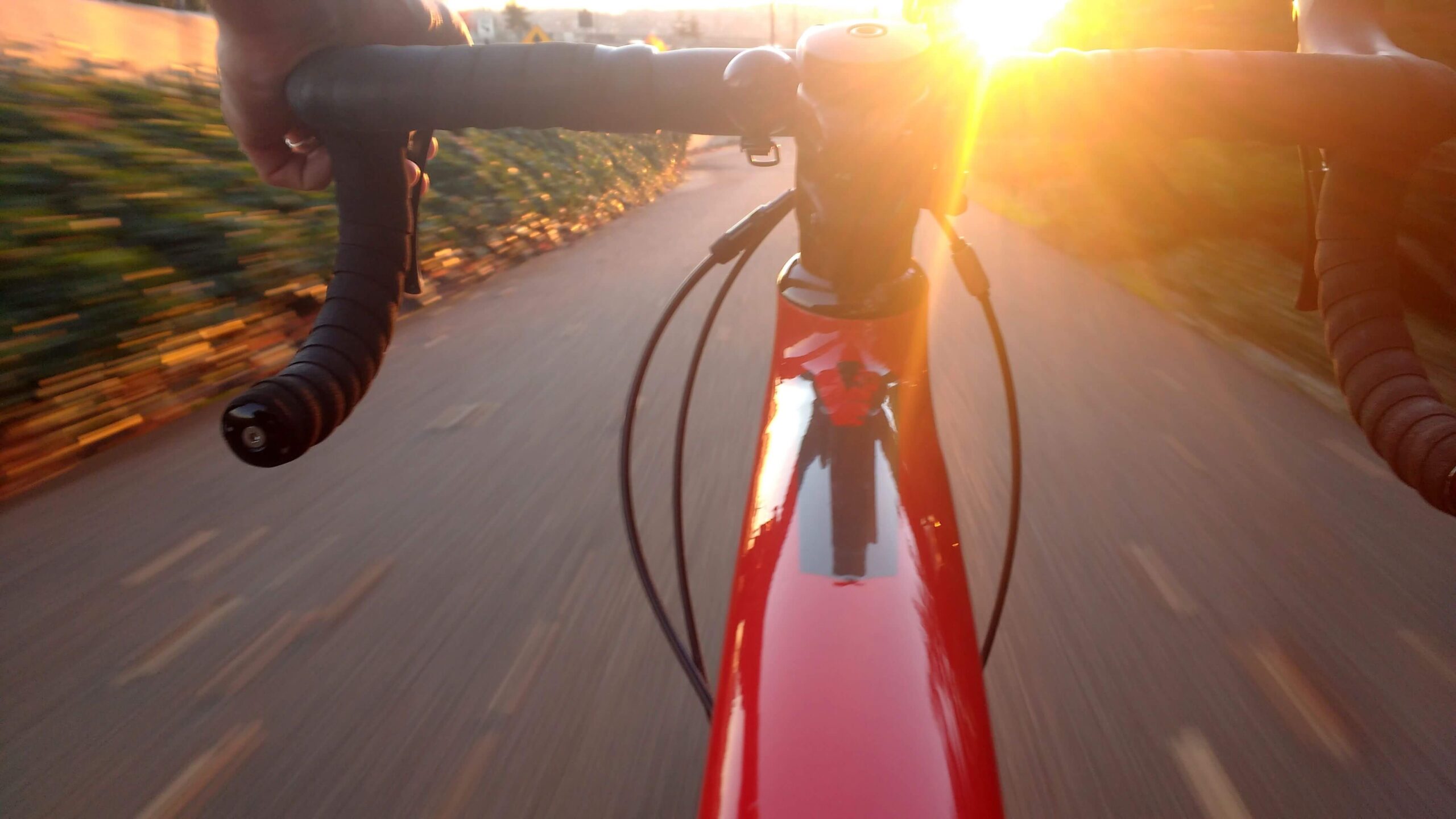 Cyclist riding a red road bike at sunset, showing the outdoor bicycle workout intensity that maximizes fat burn