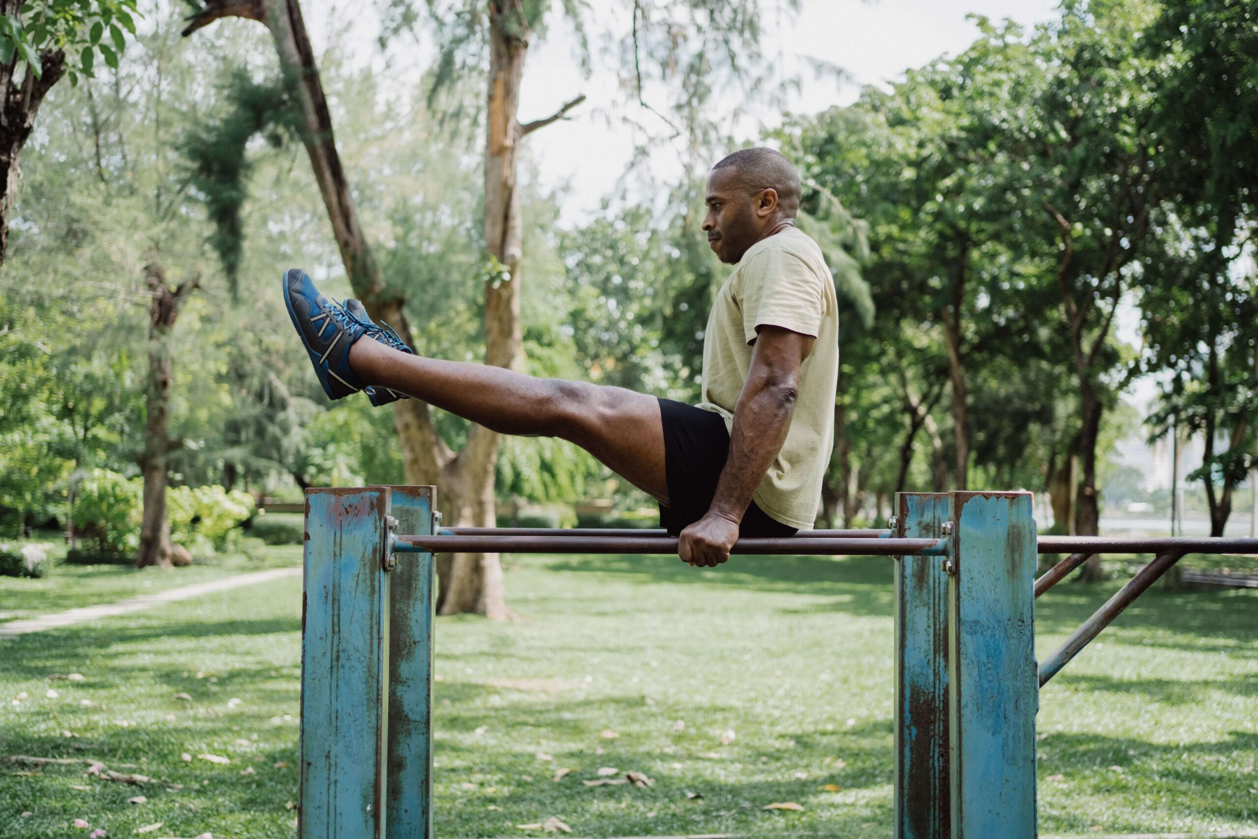 "Man performing a bodyweight calisthenics exercise using parallettes in a training facility"
