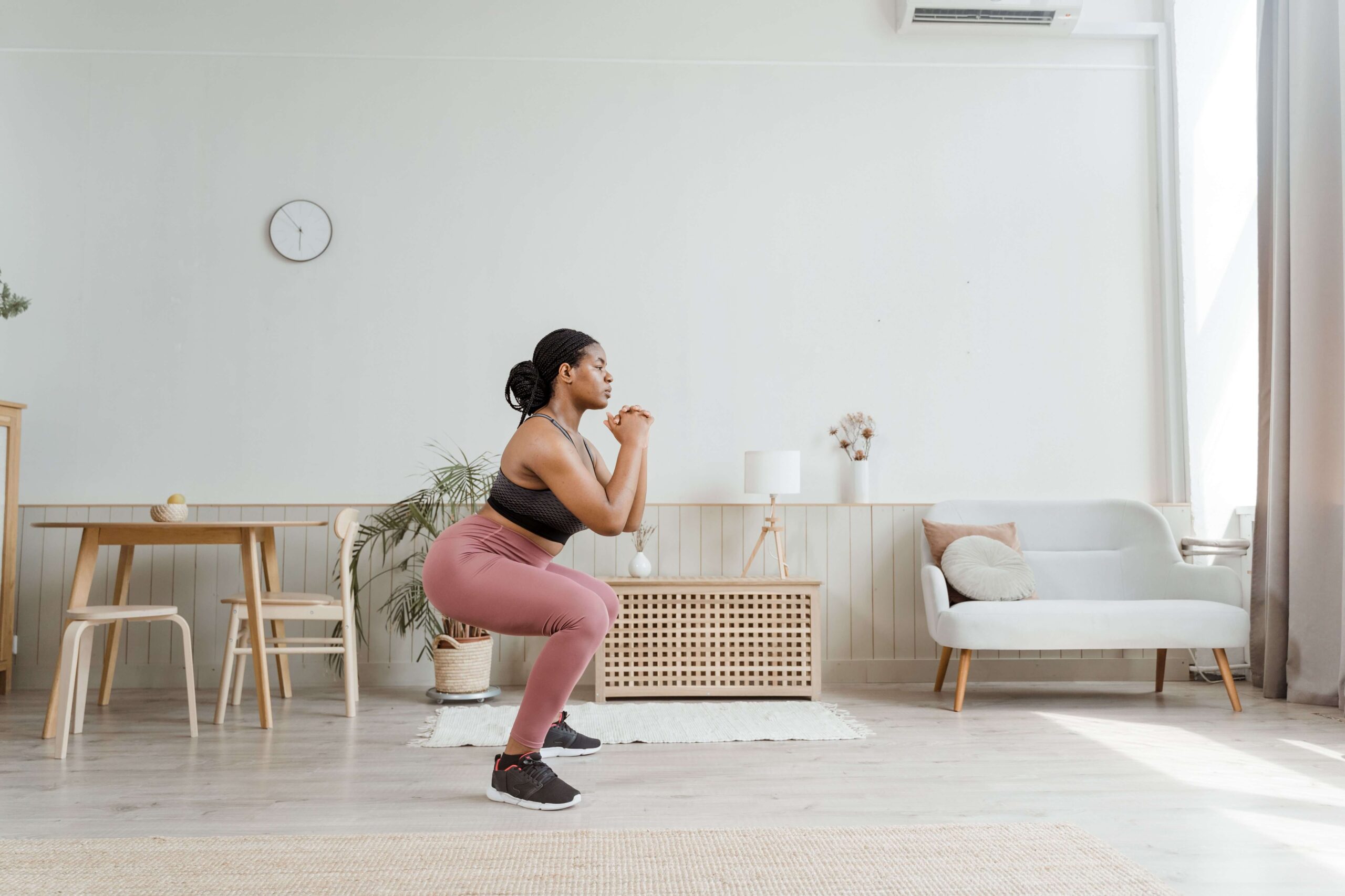 Woman doing a bodyweight squat at home as part of a calisthenics routine combining isometric and isotonic exercises